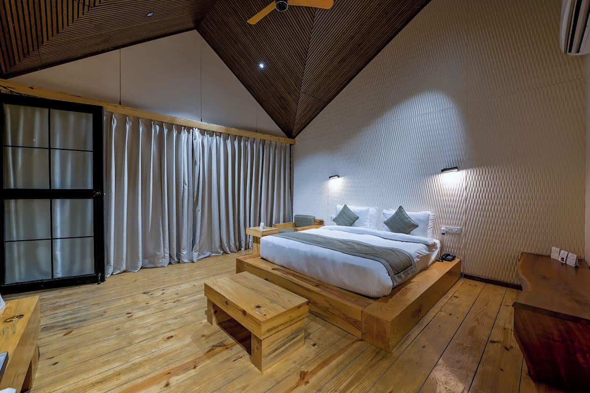 Un dormitorio moderno con una cama de madera, un banco y un ventilador de techo.