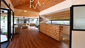 Un interior moderno con suelo de madera, una zona de estar central y un mostrador de recepción.