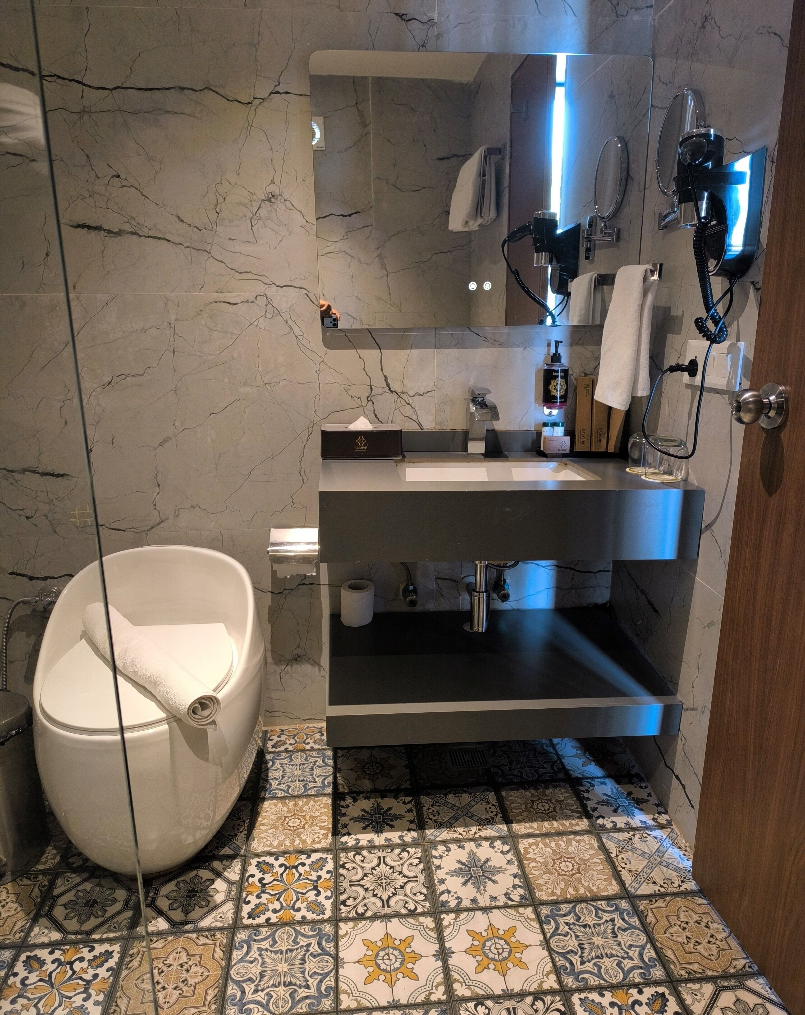 Une salle de bain avec un mur en marbre, une baignoire, un lavabo et un miroir.