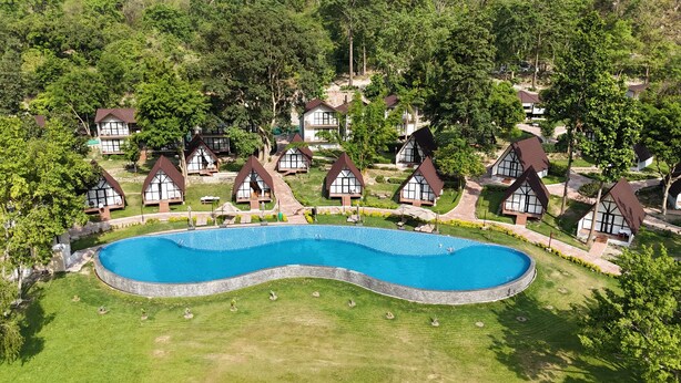 Un complejo turístico con varias cabañas tipo chalet, una piscina central y céspedes bien cuidados.