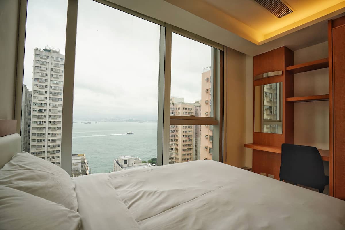 A hotel room with a large bed, a desk, and a view of the city and water.