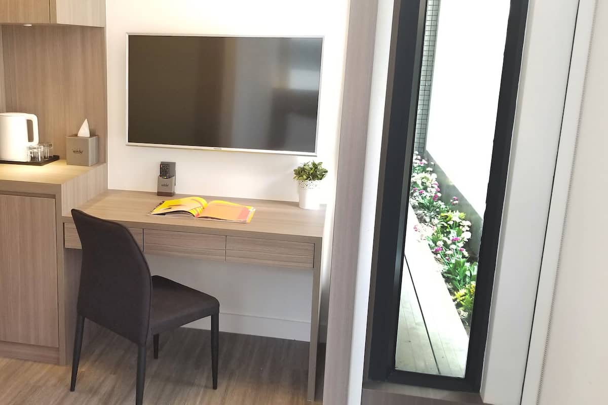 A modern kitchenette with a coffee maker, a small plant, and a window with a view of flowers.