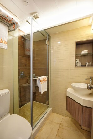 A modern bathroom with a glass-enclosed shower, a white toilet, and a vanity with a sink and mirror. - Mia Casa Hotel (Hong Kong)