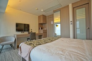 A hotel room with a bed, a desk with a flat-screen TV, a chair, and a wardrobe. - Mia Casa Hotel (Hong Kong)