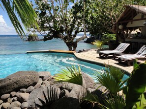 A pool area with lounge chairs, a tree, and a view of the ocean. - Seabreeze Resort Samoa - Exclusively for adults (Aufaga)