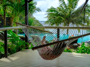 A hammock on a wooden deck overlooking a pool with palm trees in the background. - Seabreeze Resort Samoa - Exclusively for adults (Aufaga)