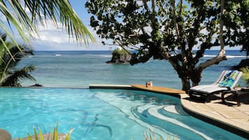 Una piscina al aire libre, sombrillas, sillones reclinables de piscina