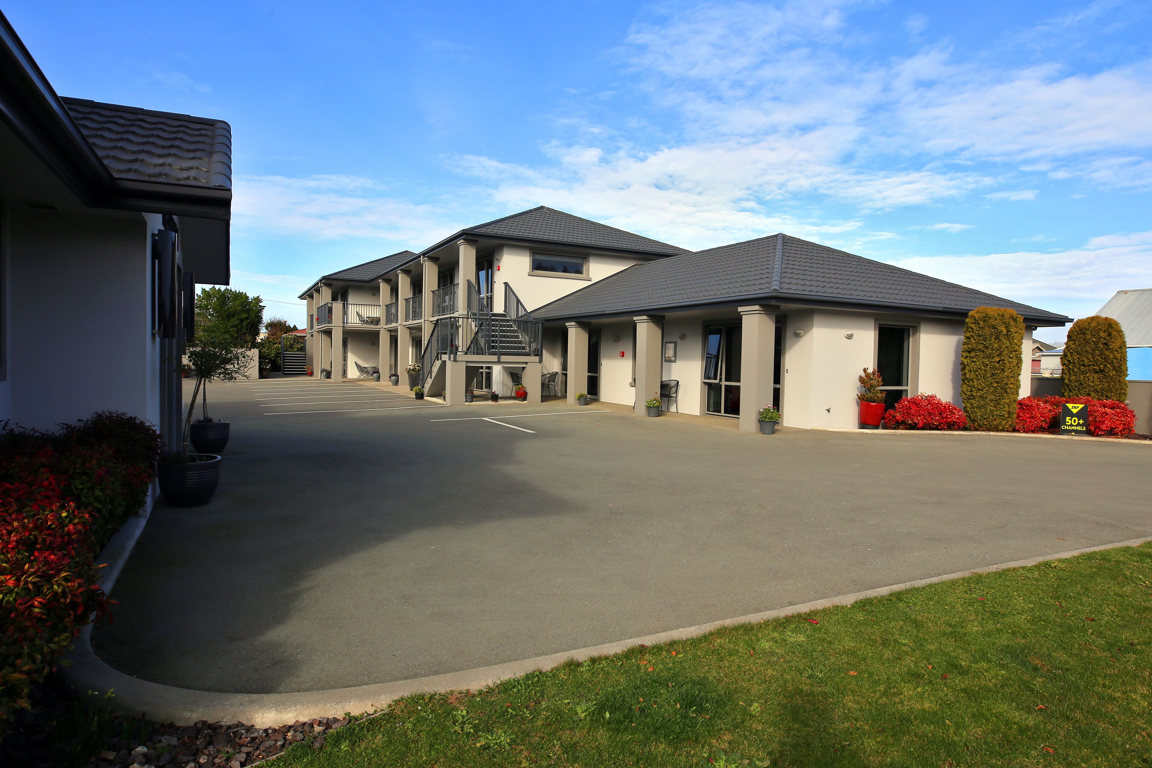 A modern building with a flat roof, a central staircase, and a covered driveway.