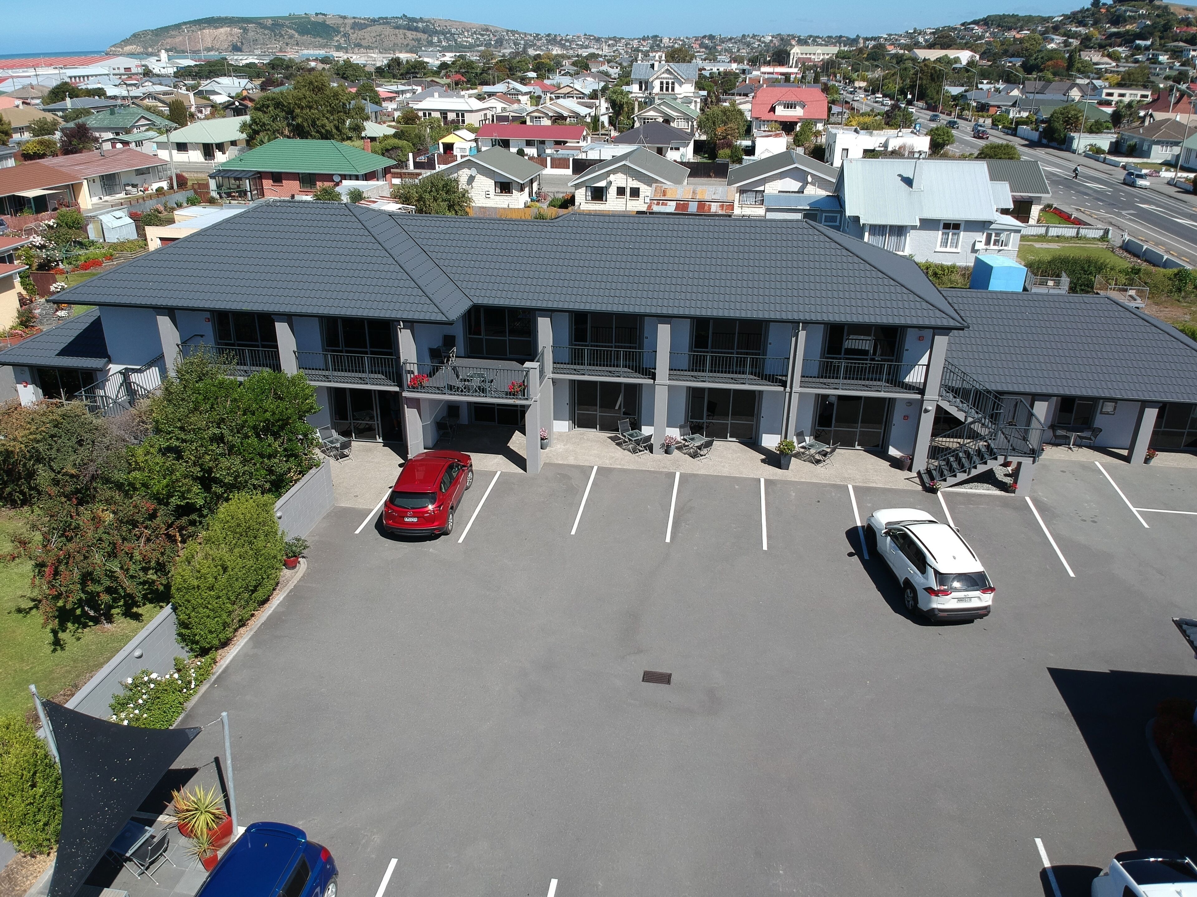 A multi-story hotel with a parking lot, outdoor seating, and a view of the surrounding neighborhood.