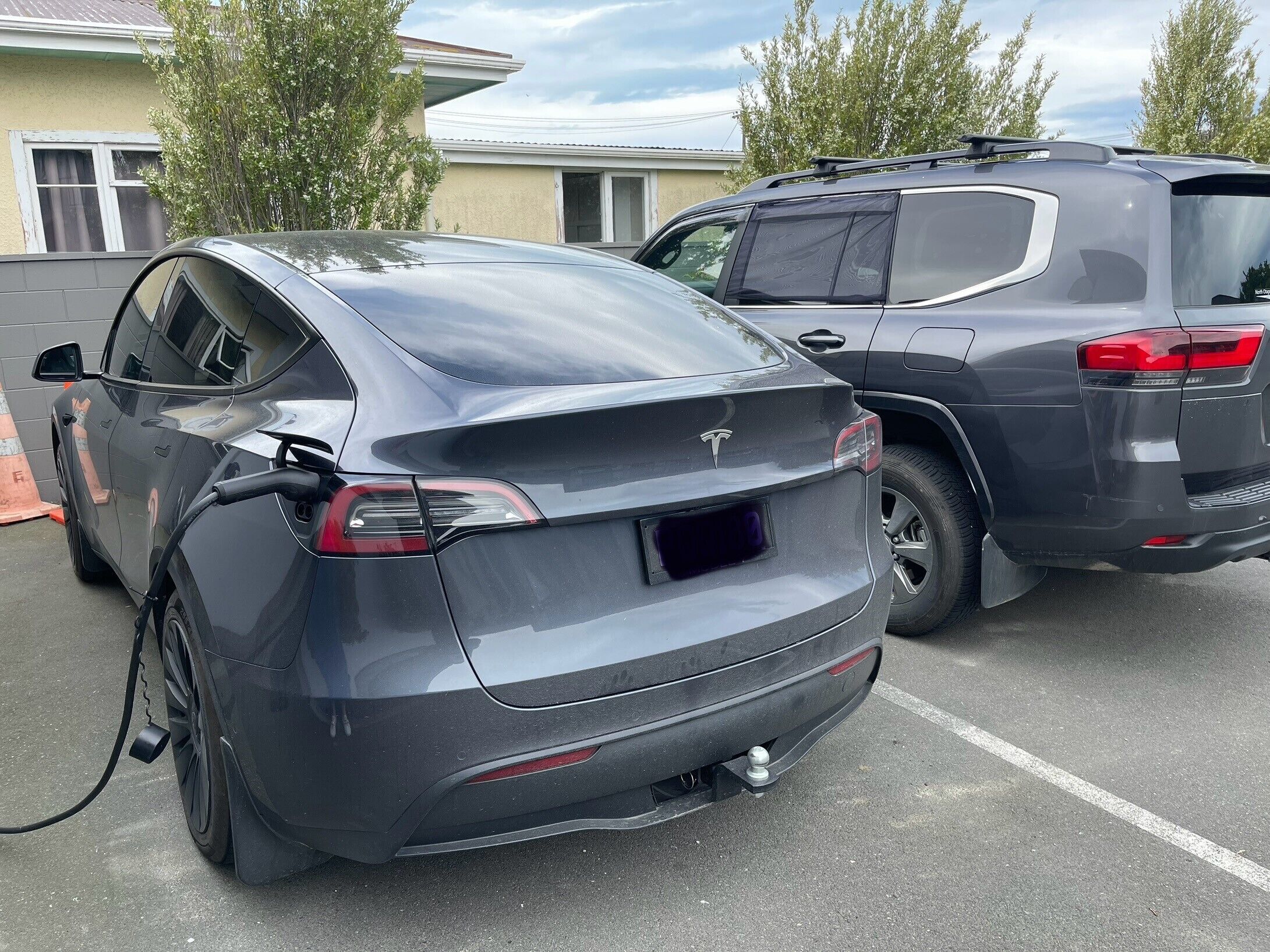 A Tesla Model 3 charging in a parking lot.