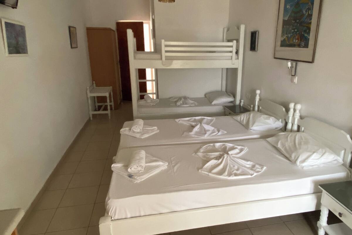 A hotel room with two beds, a small table, and a painting on the wall.