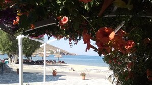 A stone-paved pathway leading to a beach with a white pergola and potted plants. - Mare Monte (Ios)
