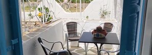 A patio area with two chairs and a table, a potted plant, and a view of the outside. - Mare Monte (Ios)