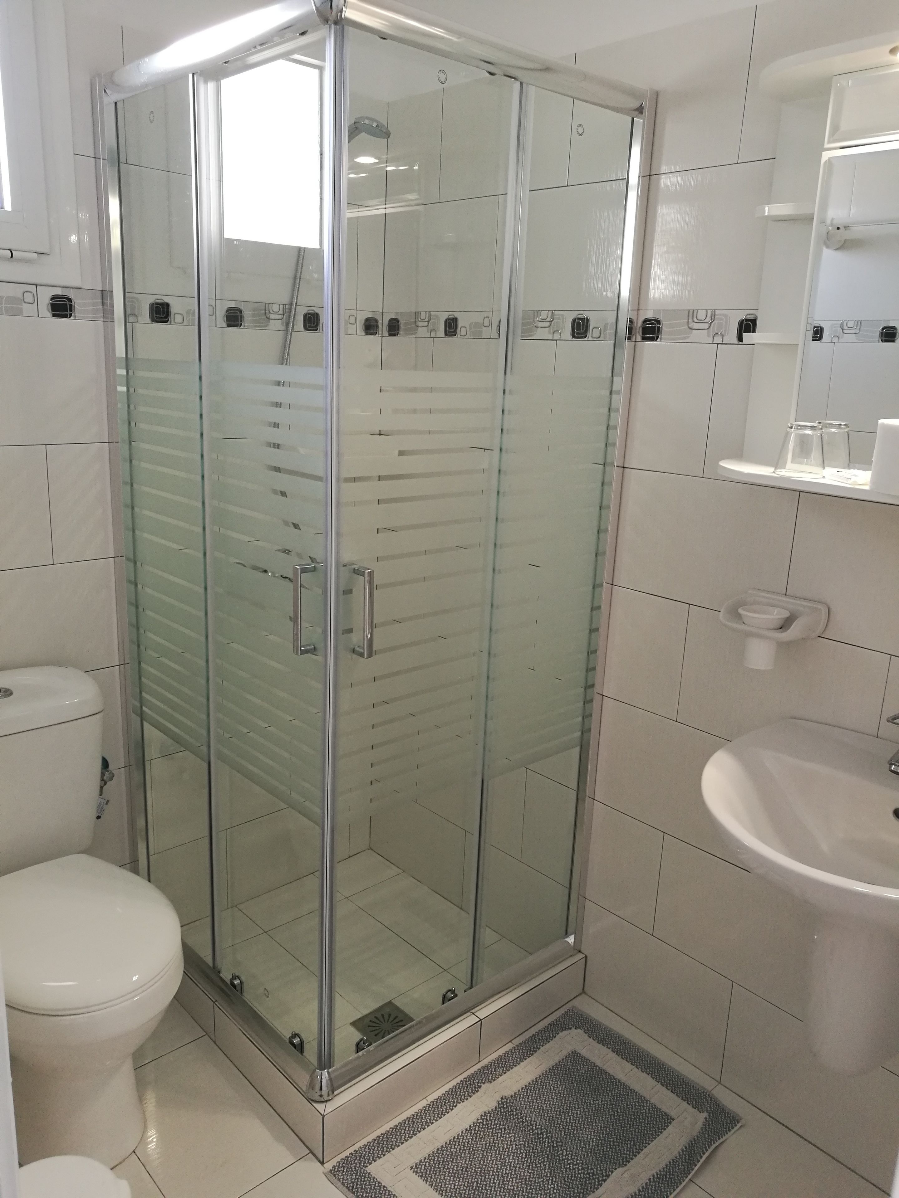 Un baño moderno con ducha de vidrio, inodoro y lavamanos.