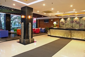 A modern lobby with a reception desk, seating area, and a decorative water feature.