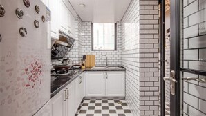 A compact kitchen with white cabinets, a black countertop, and a checkered floor. - Huaxi Angel Hotel - Chengdu (Chengdu)