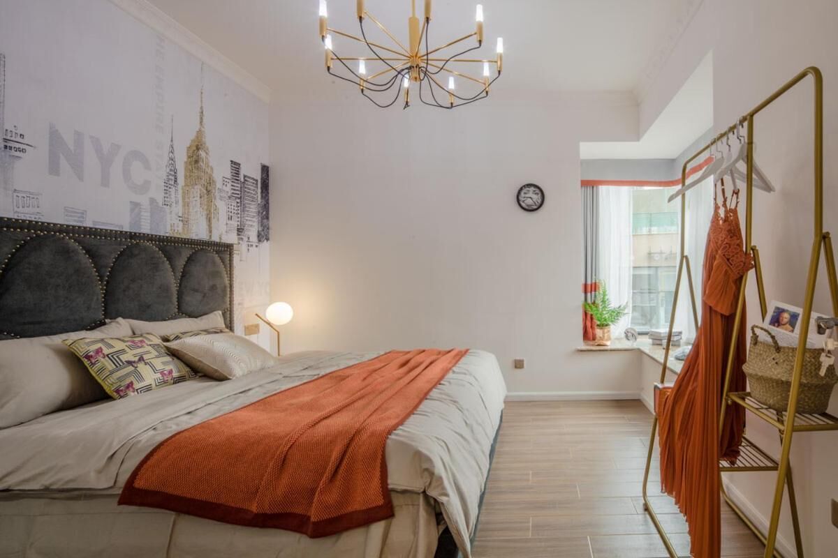 A bedroom with a bed, a wall clock, a window, and a hanging rack.