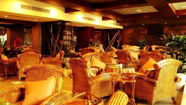 A spacious lounge area with wicker furniture and a warm, inviting atmosphere. - Huaxi Angel Hotel - Chengdu (Chengdu)