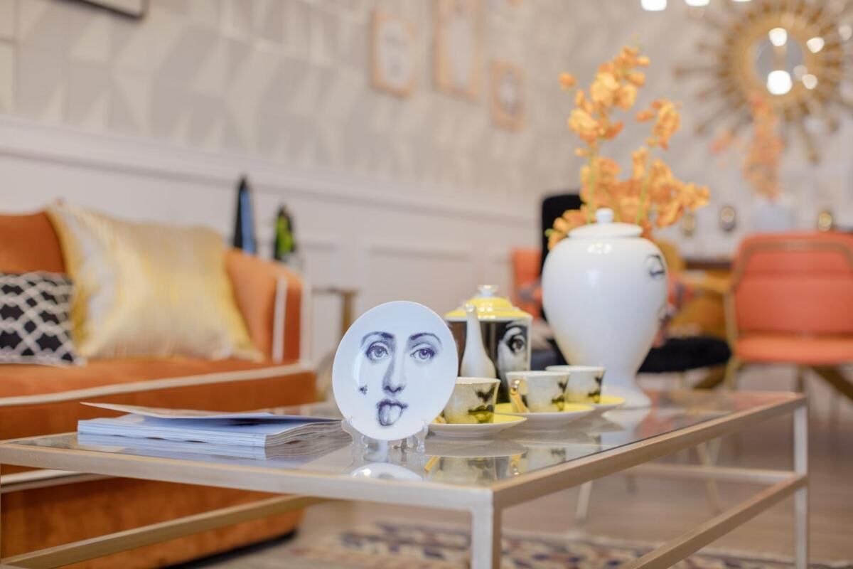 A modern living room with a sofa, a coffee table with a decorative plate, and a vase with flowers.