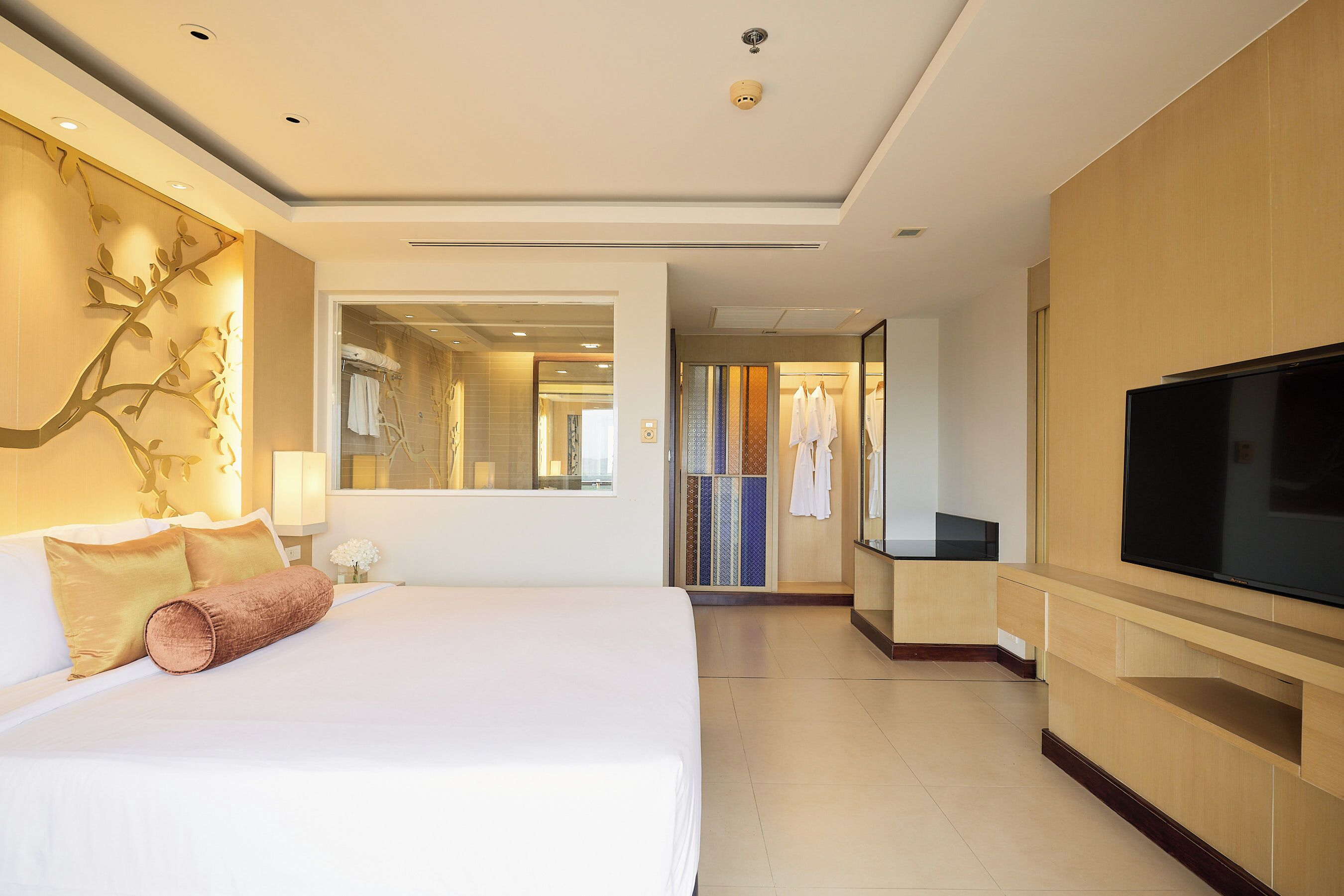 Quarto de hotel com uma cama grande, televisão e espelho.