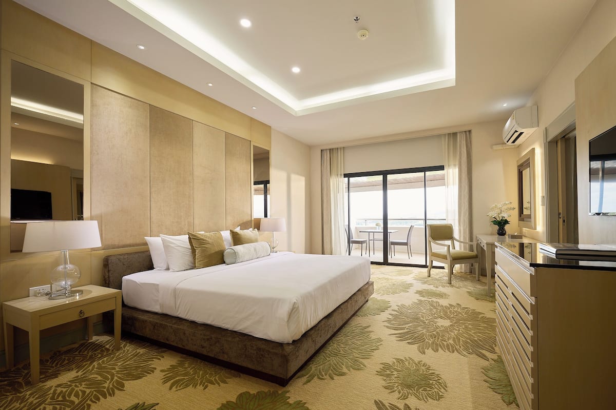 A hotel room with a large bed, a desk, a chair, and a view of the outdoors.