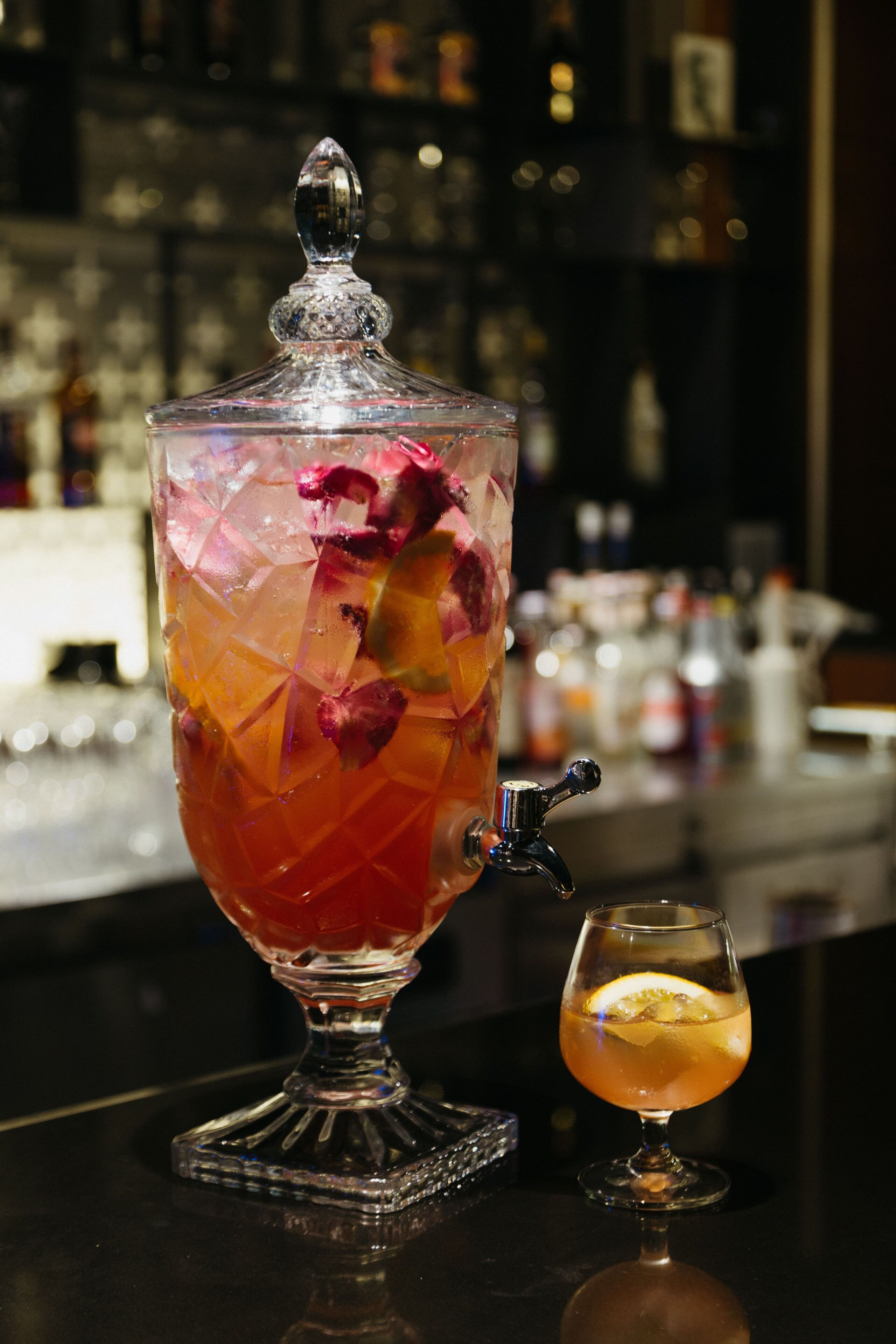 A bar setting with a large ice-filled punch bowl and a smaller glass of a beverage.