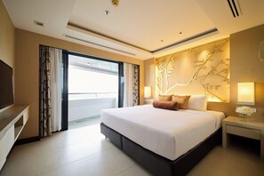 Habitación de hotel moderna con una cama grande, televisión de pantalla plana, escritorio y ventana con cortinas.