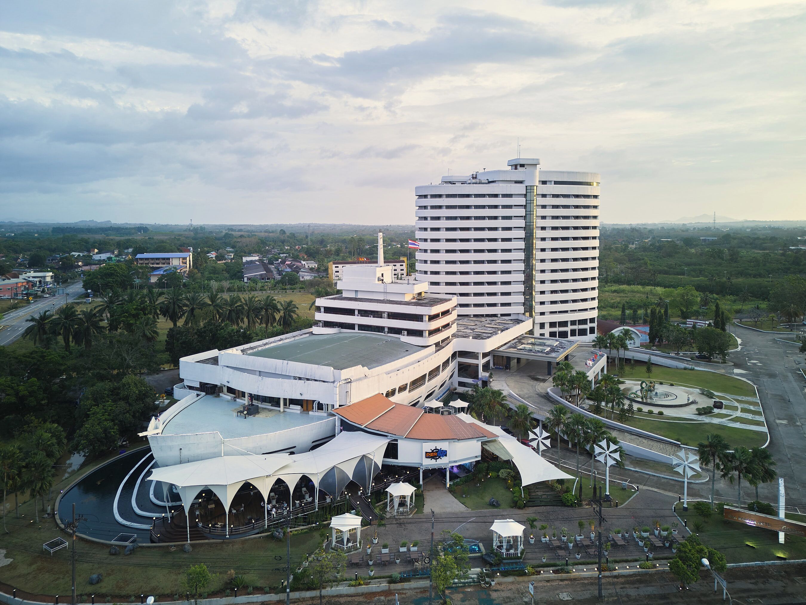 A modern hotel with a central courtyard, multiple floors, and a prominent tower.