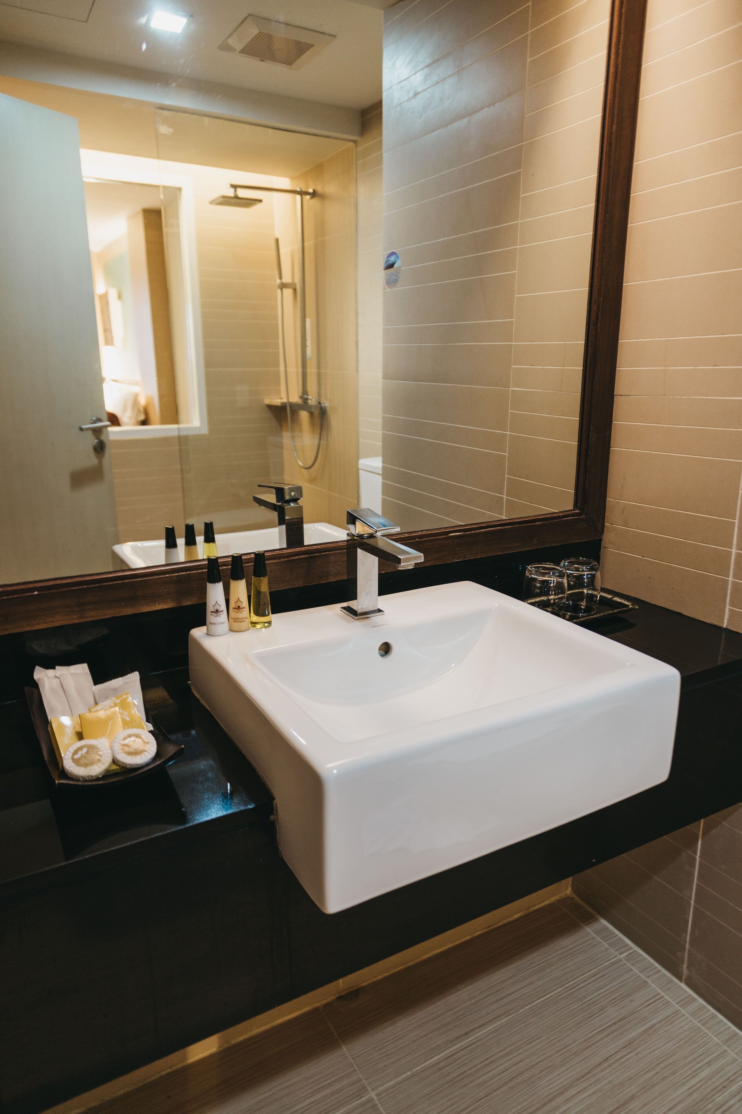 A modern bathroom with a large white sink, a mirror, and a shower area.