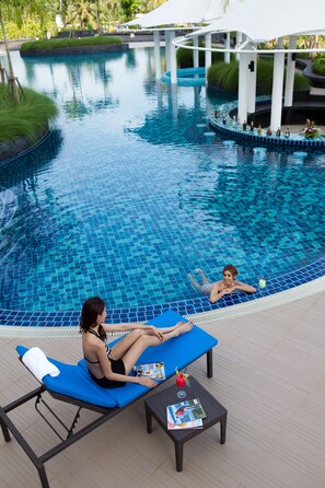 Un área junto a la piscina con sillas de descanso, una mesa pequeña con una revista y una piscina con bordes de azulejos.
