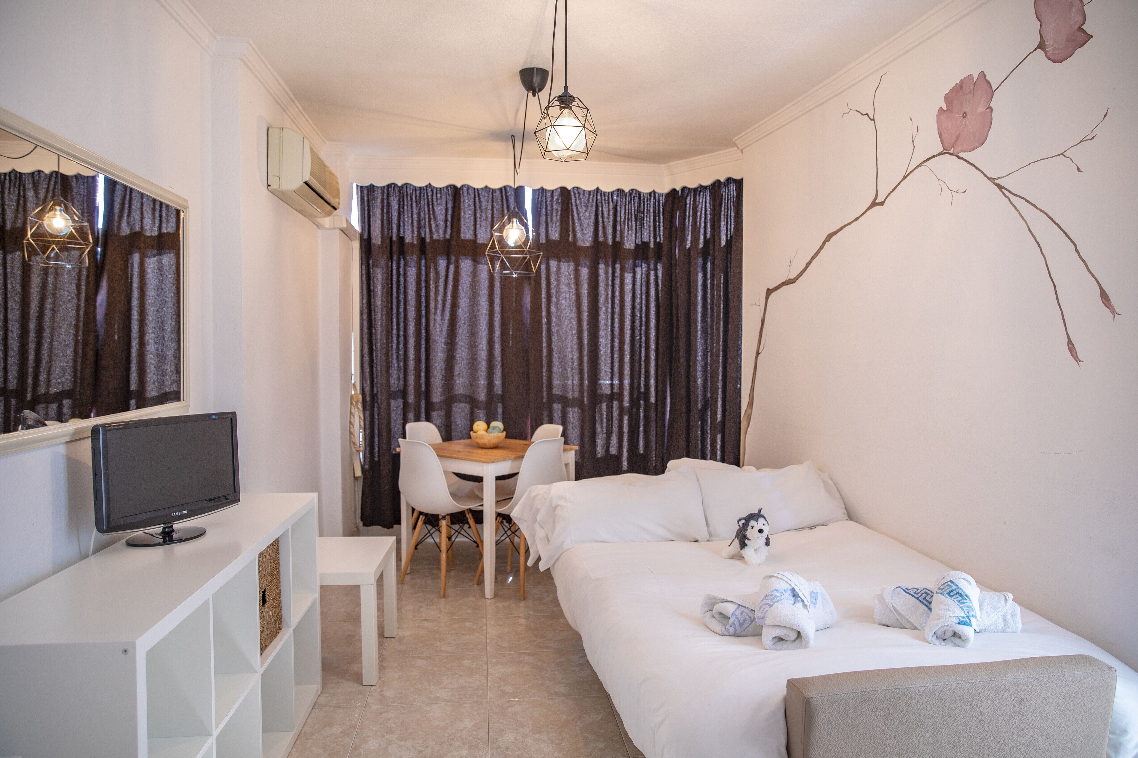 Una camera da letto con un letto, una scrivania con un computer, una sedia, un tavolo da pranzo e un condizionatore d'aria a parete.