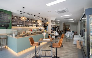 Um café moderno com um balcão central, opções de assentos e diversas comidas e bebidas à mostra.