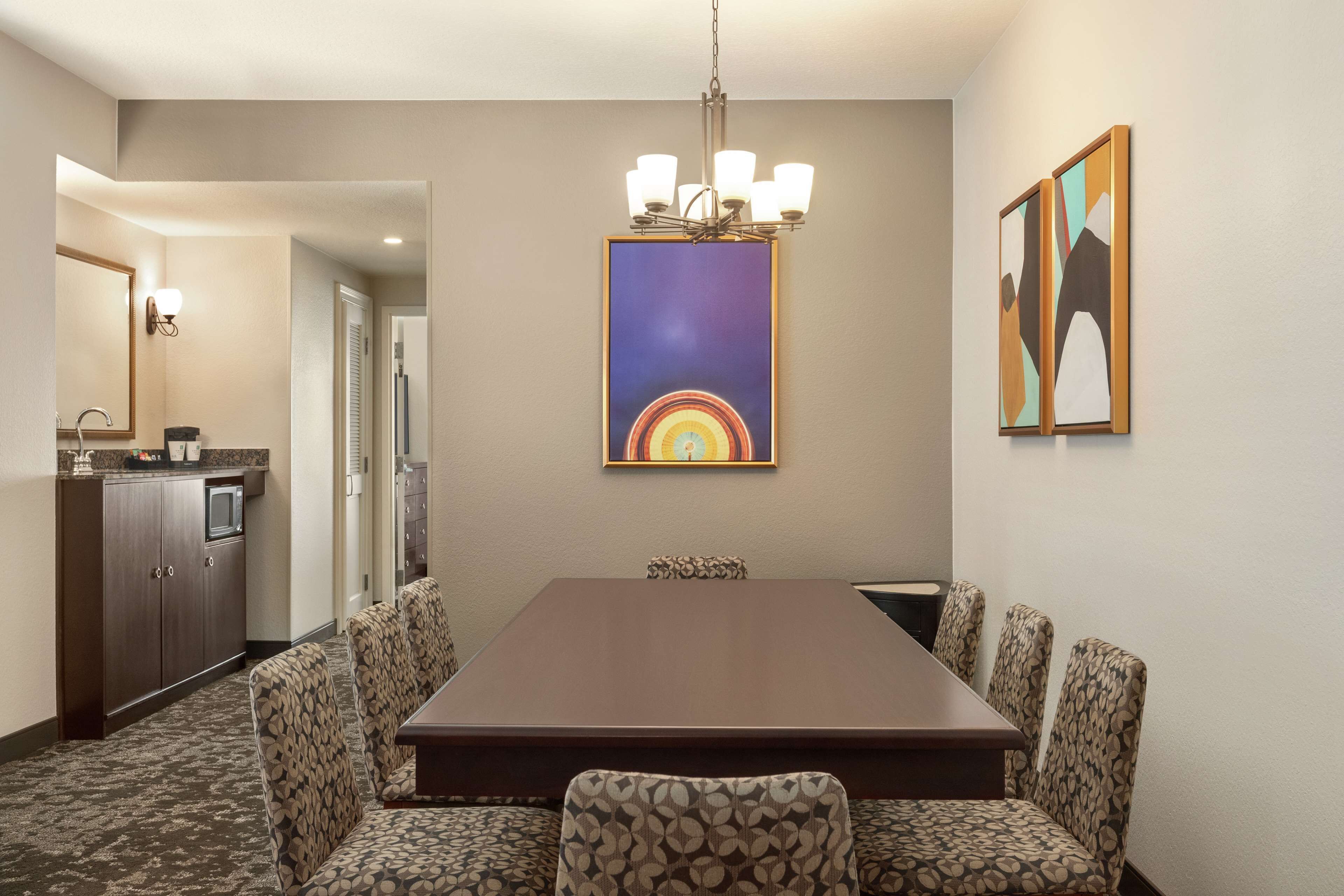 Une salle à manger d’hôtel avec une longue table, des chaises à motifs, un lustre et des œuvres d’art accrochées aux murs.