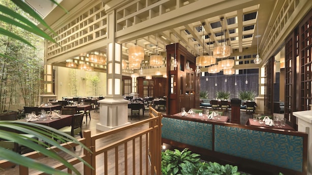 A spacious restaurant with high ceilings, hanging pendant lights, and a variety of seating arrangements. - Embassy Suites by Hilton Orlando Lake Buena Vista South (Kissimmee)