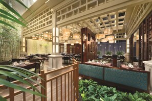 A spacious restaurant with high ceilings, hanging pendant lights, and a variety of seating arrangements.