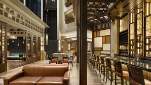 A spacious lobby with a leather sofa, a bar area with stools, and a seating area with tables and chairs. - Embassy Suites by Hilton Orlando Lake Buena Vista South (Kissimmee)