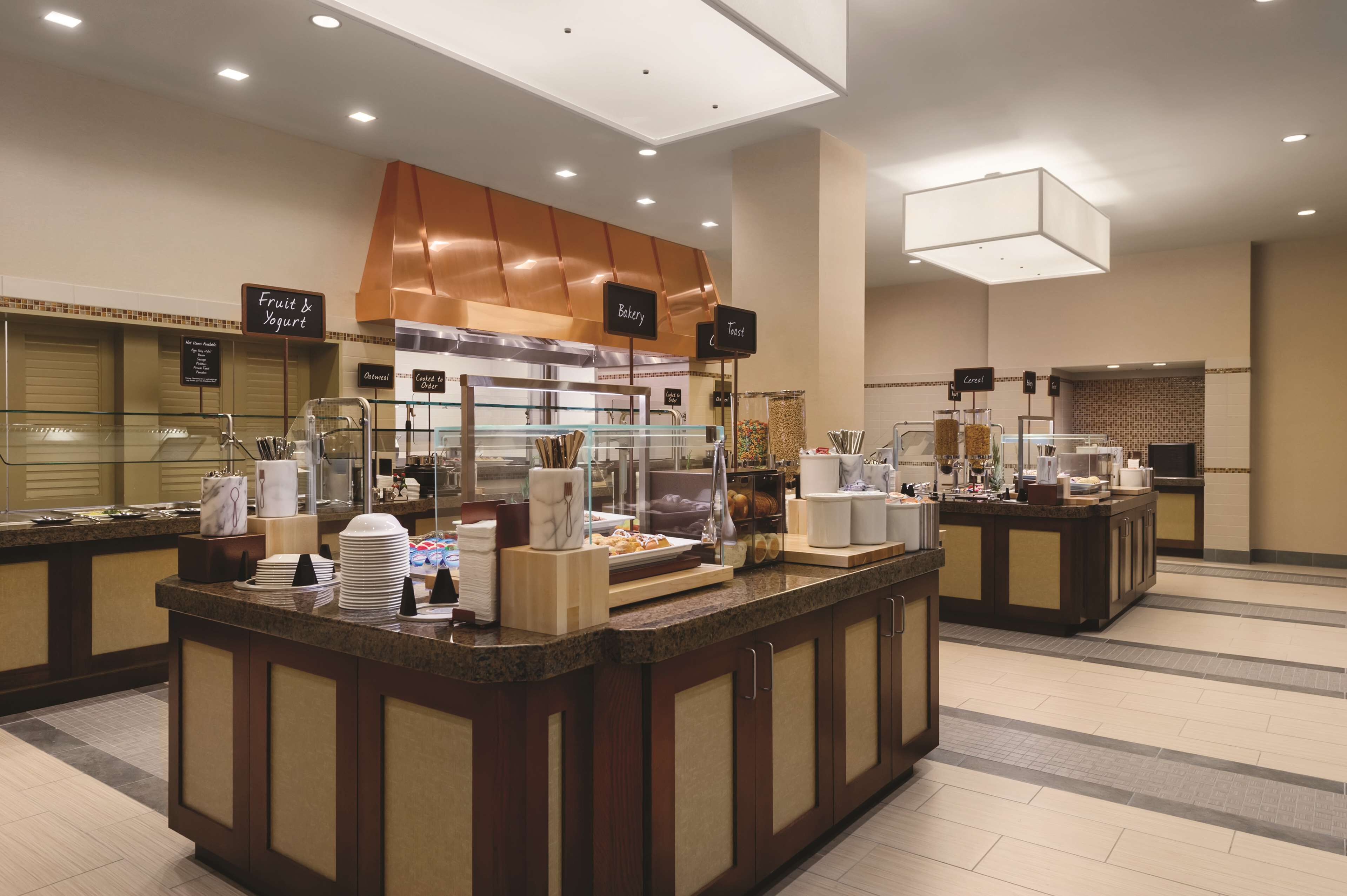 A hotel breakfast area with self-serve stations for fruit & yogurt, bakery, and coffee.