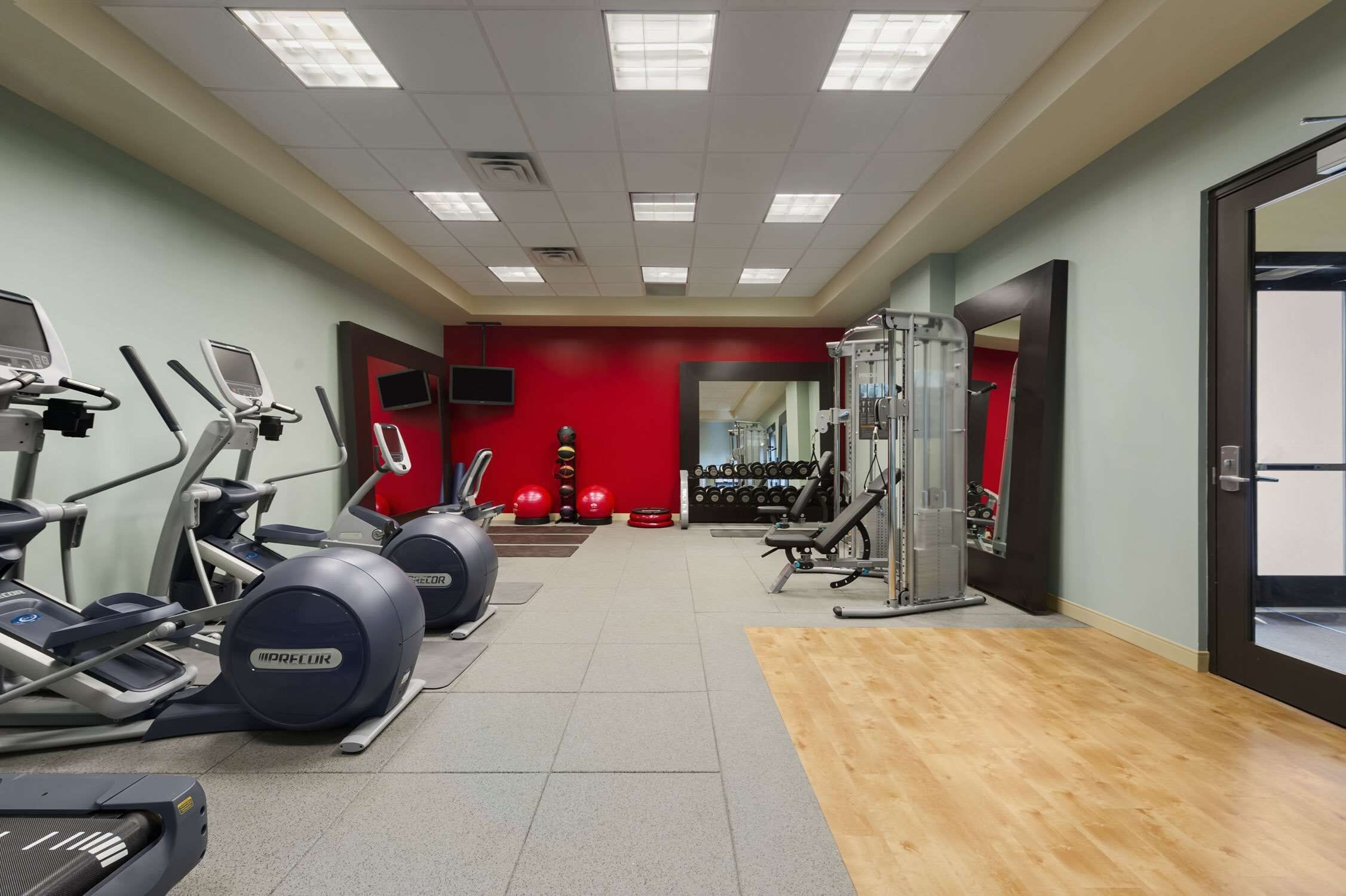 Un gimnasio con cintas de correr, elípticas y pesas libres.