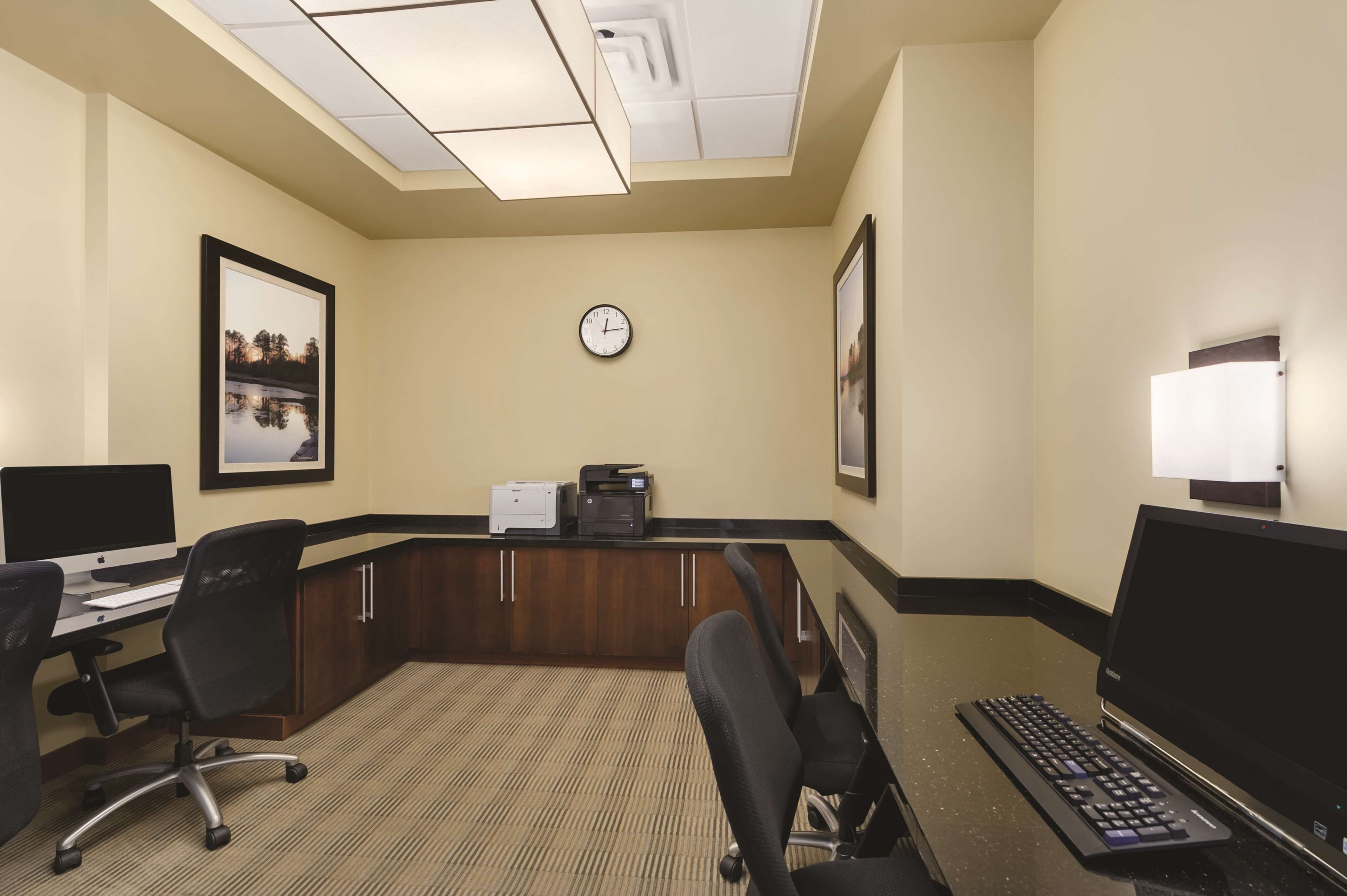 A conference room with a desk, two chairs, a clock, and a printer.