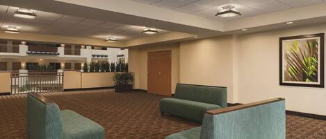 A hotel lobby with a reception desk, seating area, and a door.