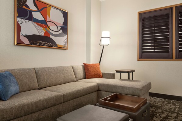 A sectional sofa with a geometric-patterned pillow, a small side table, and a floor lamp.