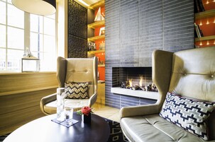 Ein gemütliches Wohnzimmer mit Ledersofas, einem Kamin und einem Bücherregal.
