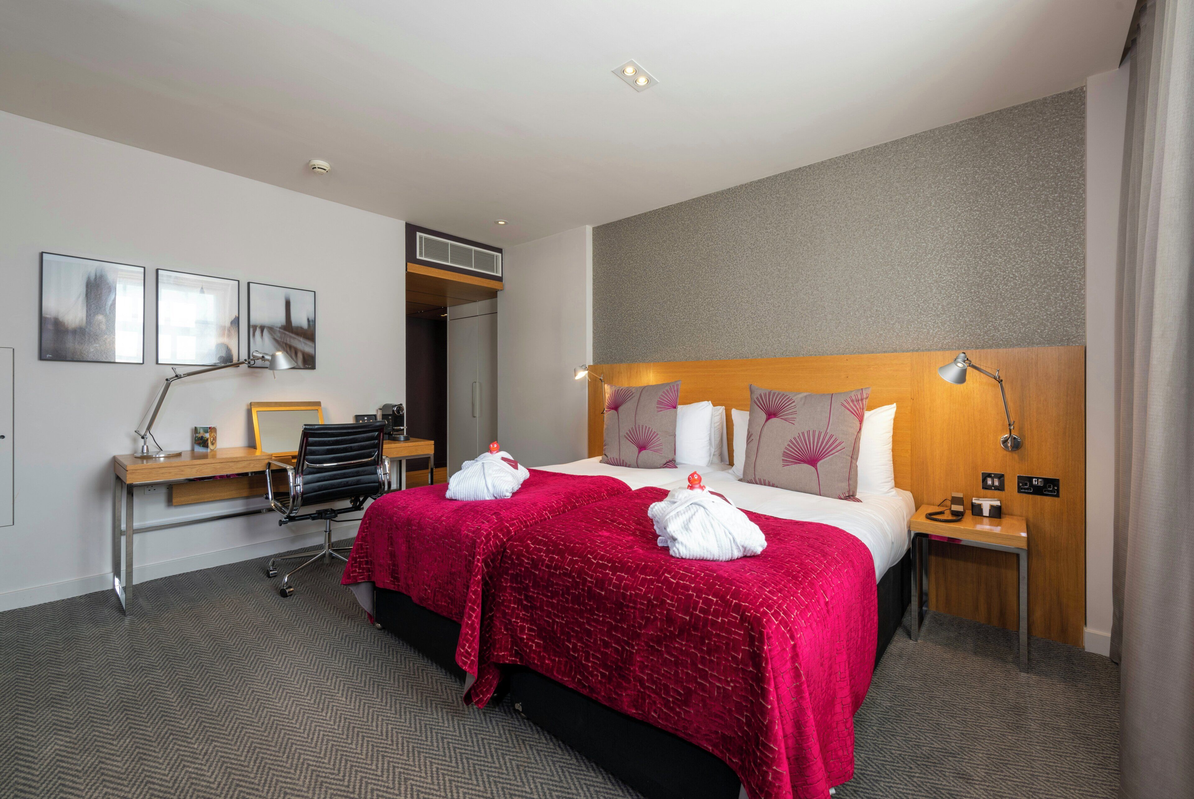 Una habitación de hotel con cama, escritorio, silla y vistas a la ciudad.