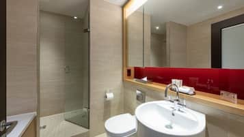 A modern bathroom with a glass-enclosed shower, a white sink, and a red accent wall.