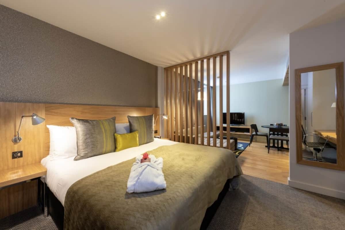 A hotel room with a large bed, a desk, and a chair.