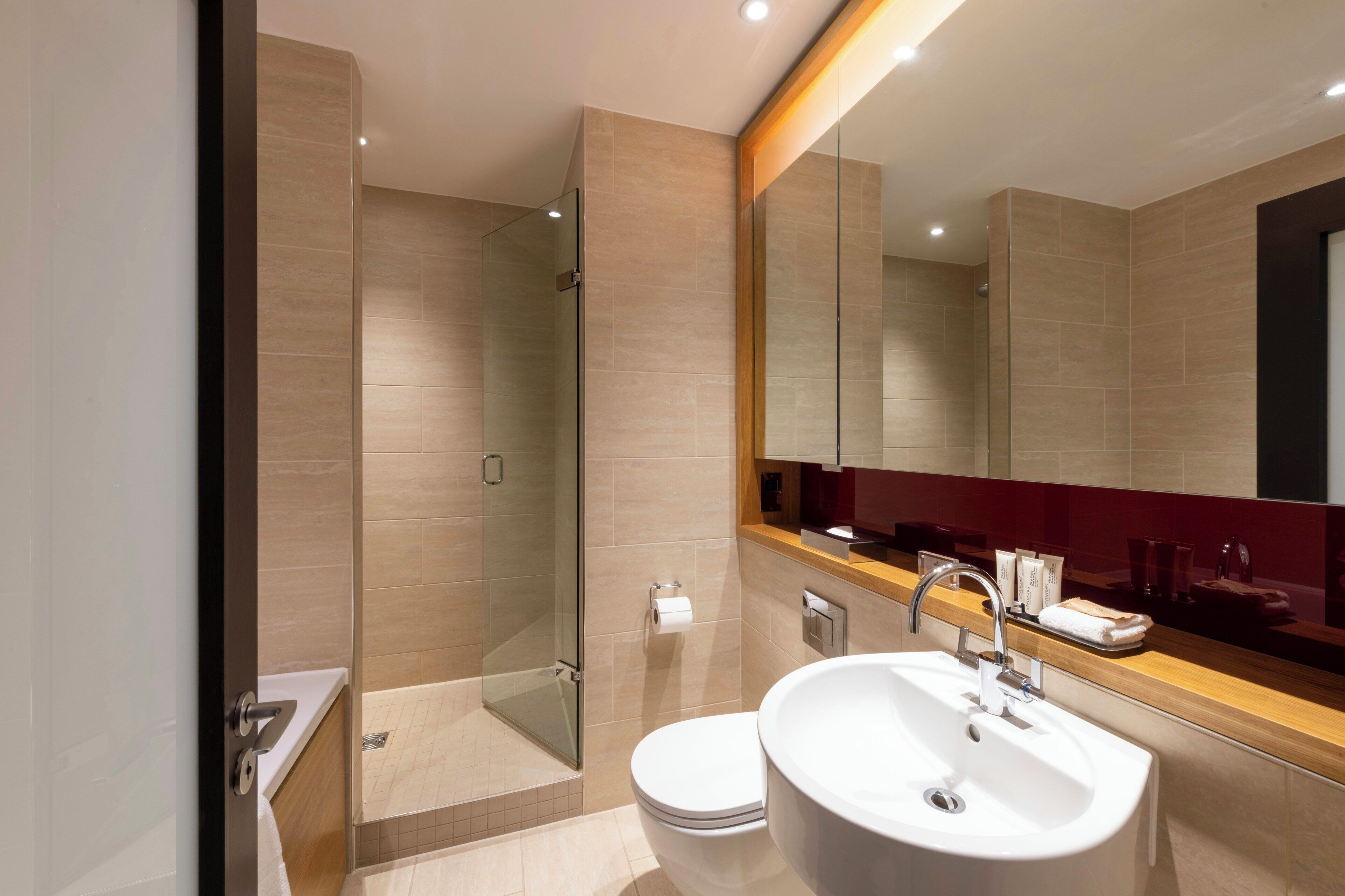 A modern bathroom with a glass-enclosed shower, a white sink, and a large mirror.