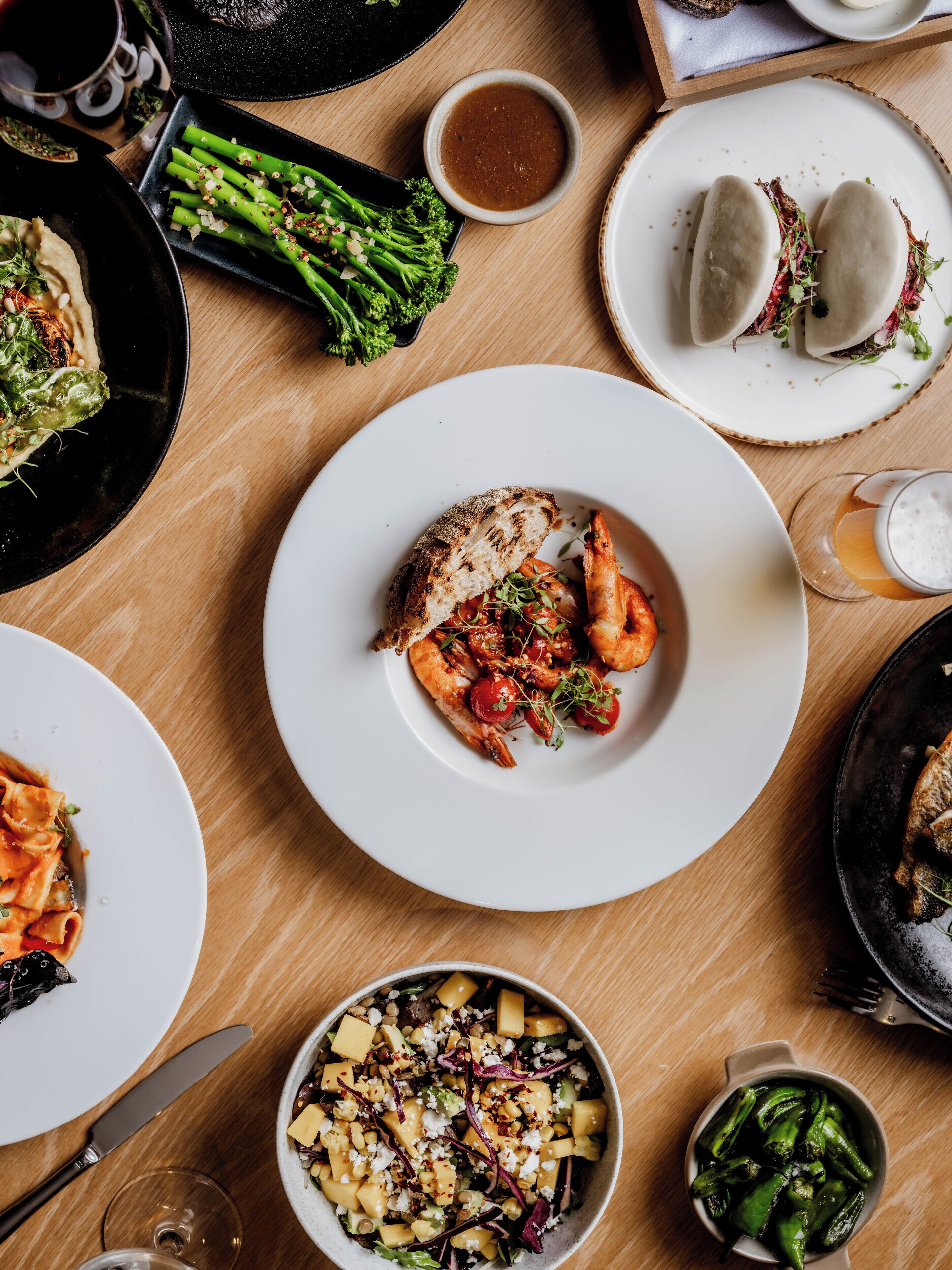 A dining table with various dishes, including a plate of shrimp, a bowl of salad, and a plate of dumplings.