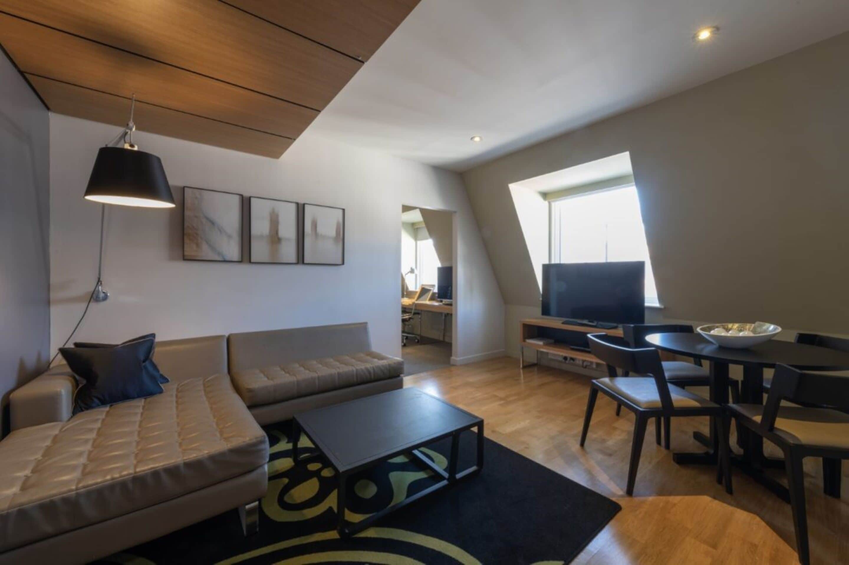 Una sala de estar moderna con sofá, mesa de centro, televisor y comedor.