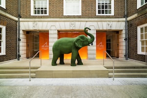 A large green elephant statue in front of a building with the sign "Apex Hotels Temple Court Luxury."