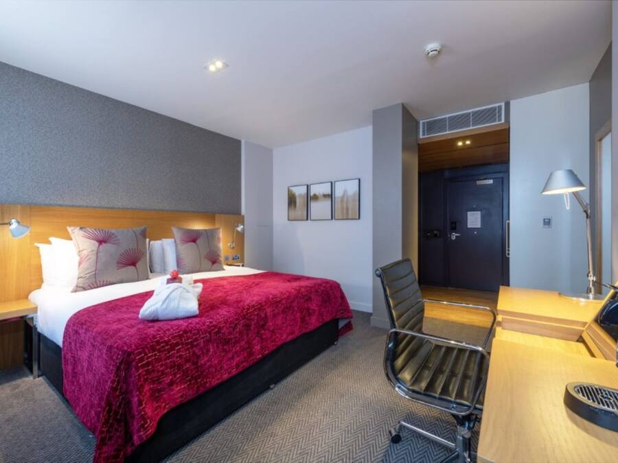 Ein Hotelzimmer mit Bett, Schreibtisch, Stuhl und einer Tür zu einem Badezimmer.